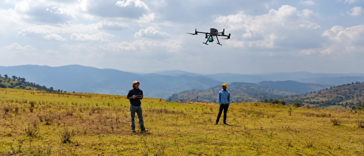 Two field operators watching an aircraft above the Uganda hills; AI-assisted composition